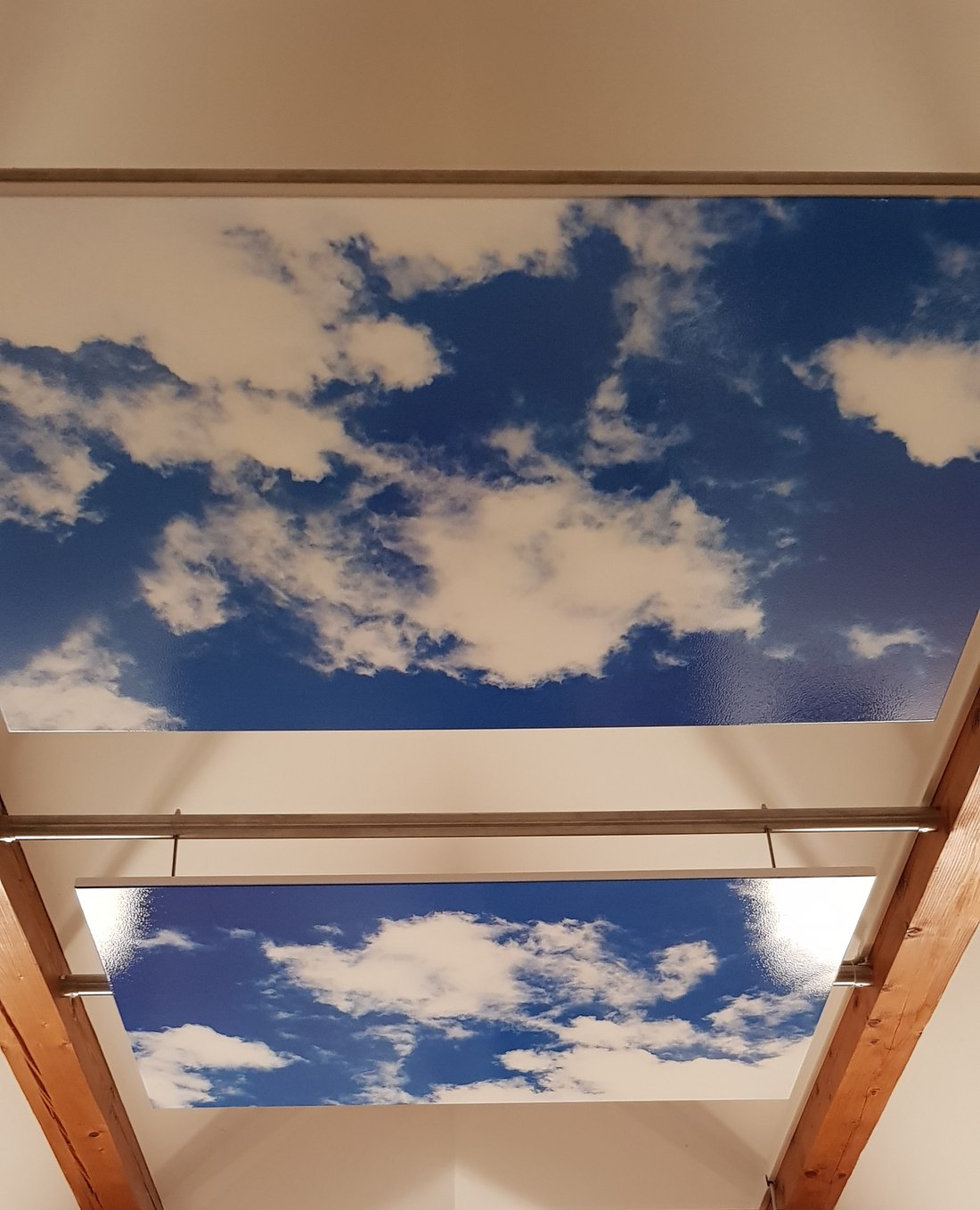 Hochglaenzend bedruckte S-Deluxe-Paneele mit Himmelsmotiv an der Decke eines Ferienhauses